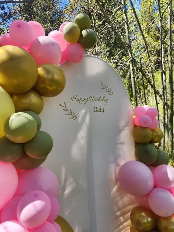 Blush, pink, and sage balloons around an arched birthday backdrop