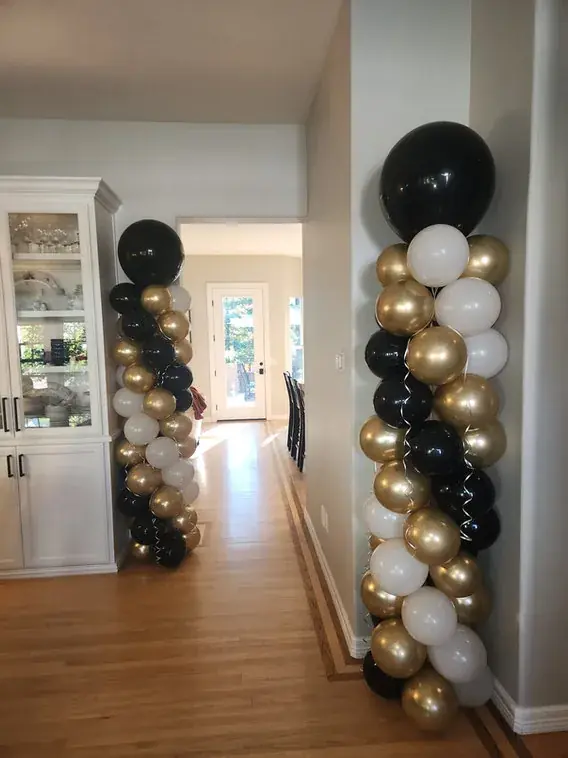 Black, white, and gold balloon columns in a hallway