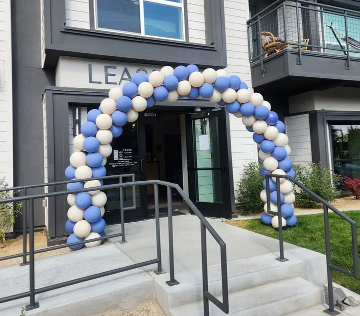 Blue and white balloon arch over an apartment leasing office entrance