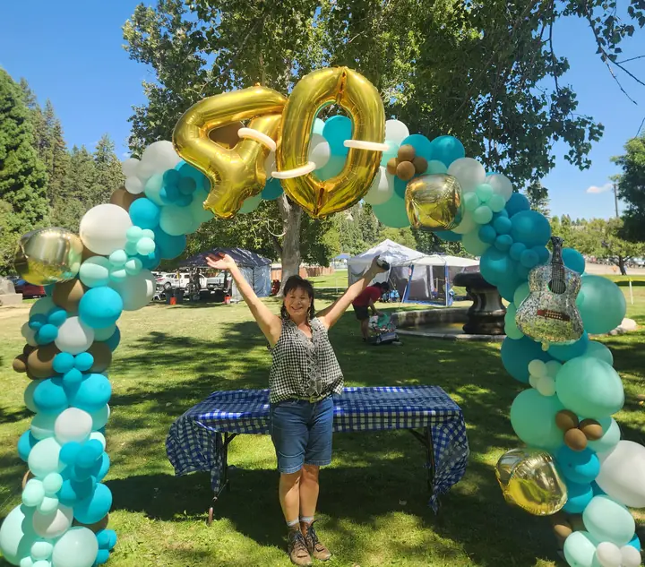 Teal, white, and gold organic balloon arch with gold 40 number balloons at an outdoor party