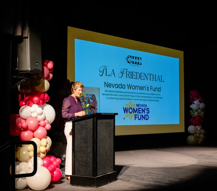Pink and cream organic balloon columns flanking the stage at a Nevada Women's Fund event