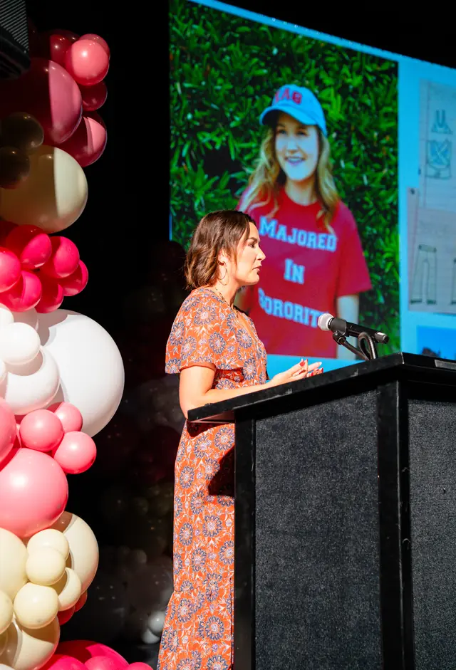 Pink and cream organic balloon column beside a speaker at a podium